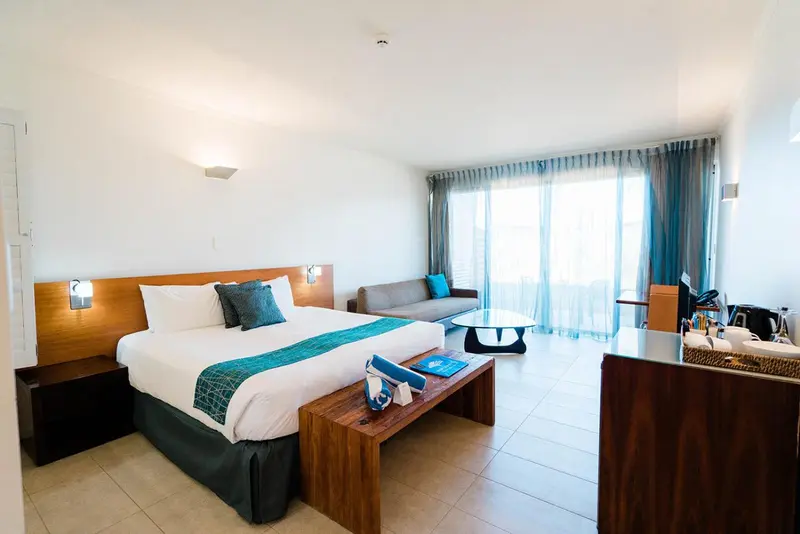 Une chambre lumineuse avec un grand lit et un coin salon.