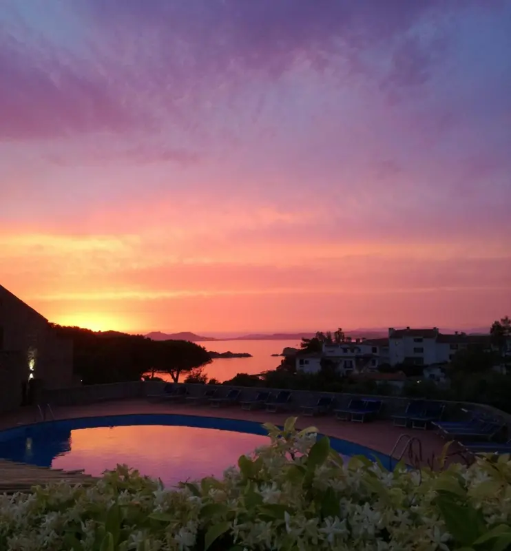 Ciel flamboyant au coucher du soleil sur une piscine et des bâtiments.