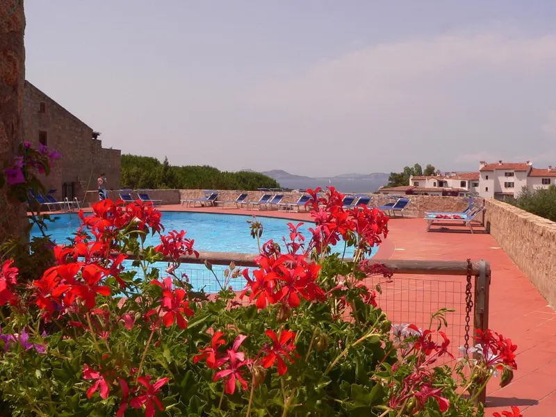 Terrasse fleurie surplombant une piscine et un paysage côtier.