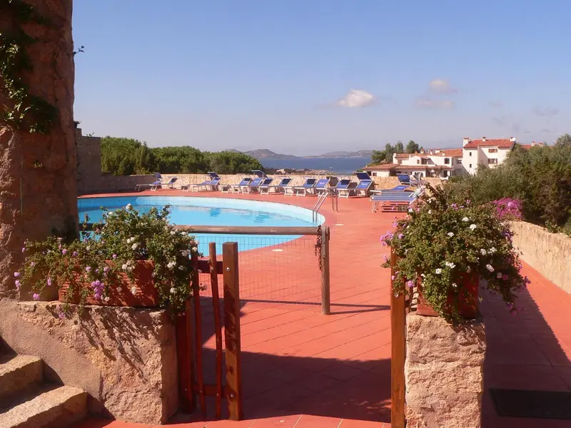 Terrasse avec piscine et transats ensoleillés.