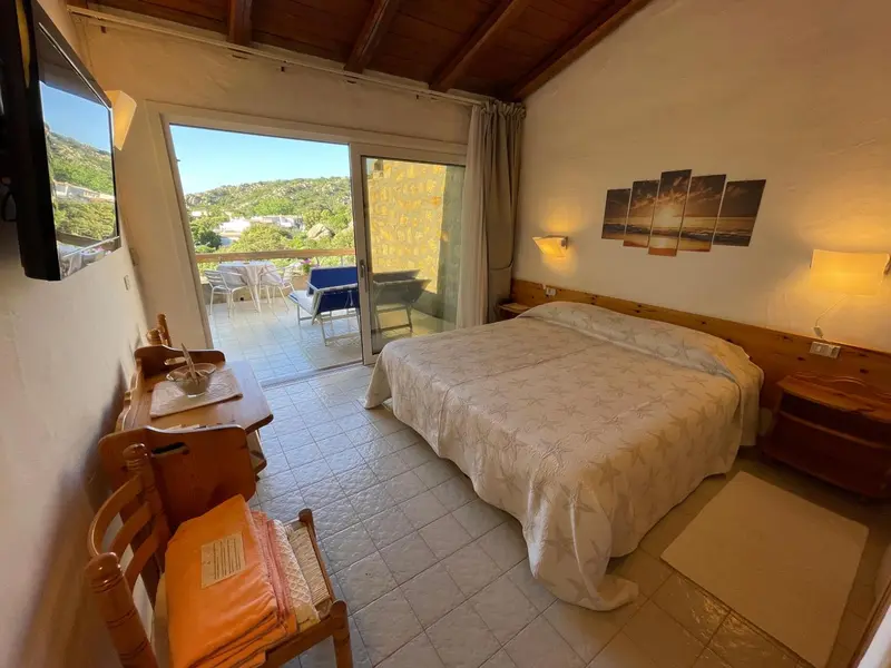Une chambre lumineuse s'ouvre sur une terrasse avec vue sur le paysage.