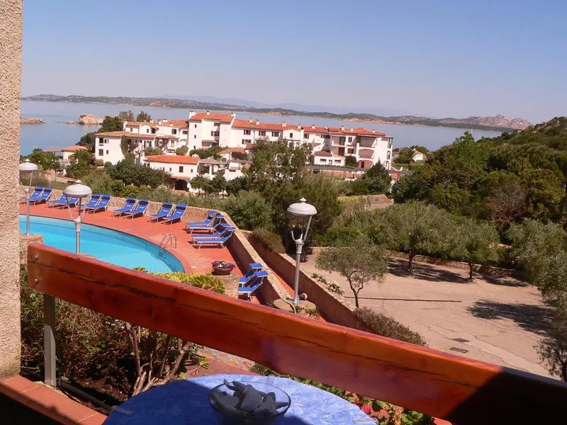 Vue d'un complexe hôtelier avec piscine et végétation luxuriante surplombant la mer.