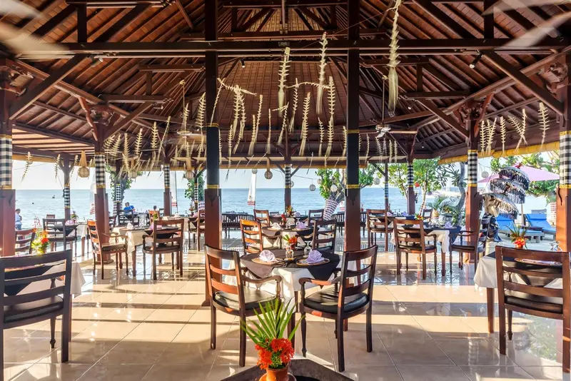 Une salle à manger ouverte sur la mer avec des tables dressées.