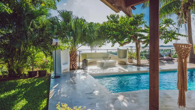 Espace de détente extérieur avec piscine et végétation tropicale.