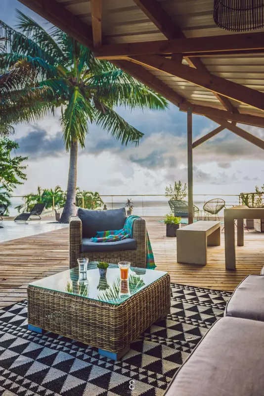 Espace de détente extérieur avec mobilier en rotin et vue sur la mer.