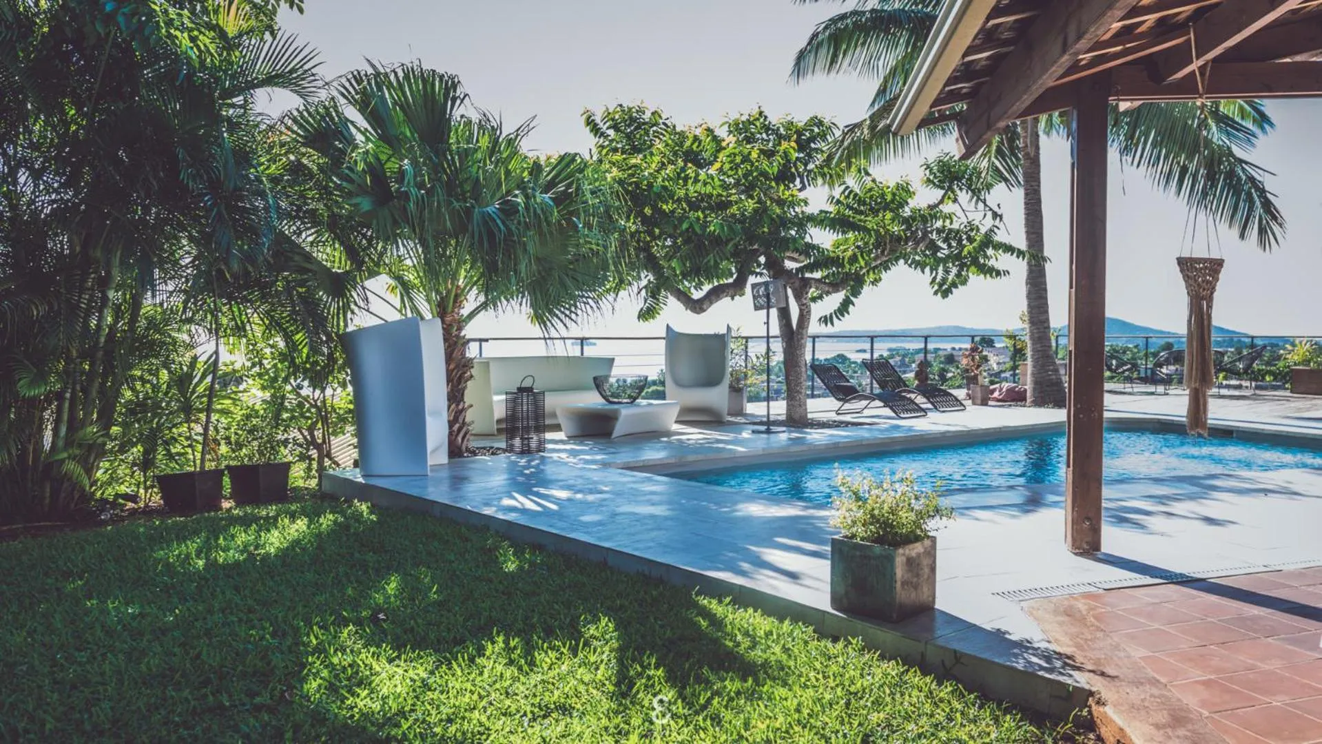 Terrasse avec piscine et mobilier de détente face à la mer.
