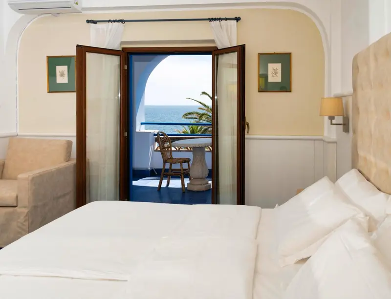 Une chambre lumineuse s'ouvre sur une terrasse avec vue sur la mer.
