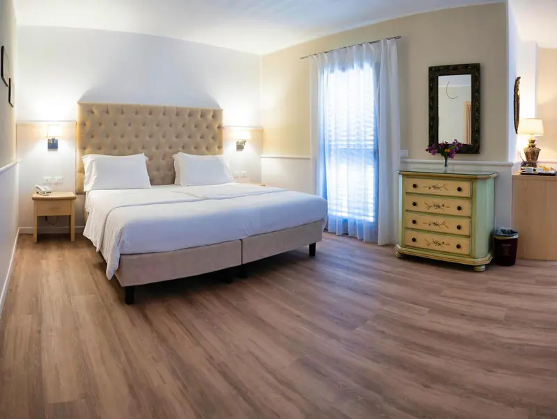 Une chambre lumineuse avec un grand lit recouvert d'une courtepointe blanche.