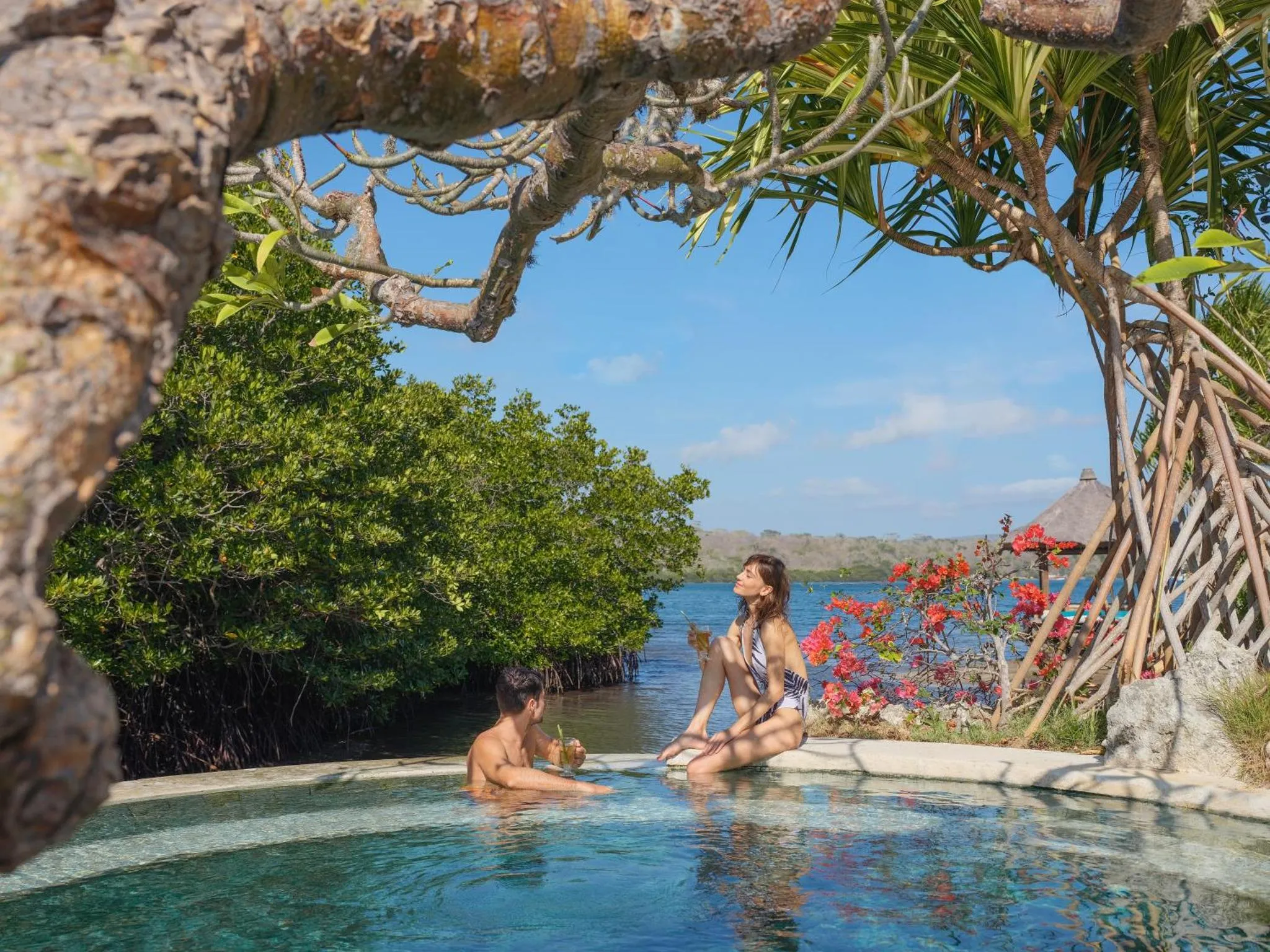 Un couple se détend dans une piscine à débordement avec vue sur la mer.