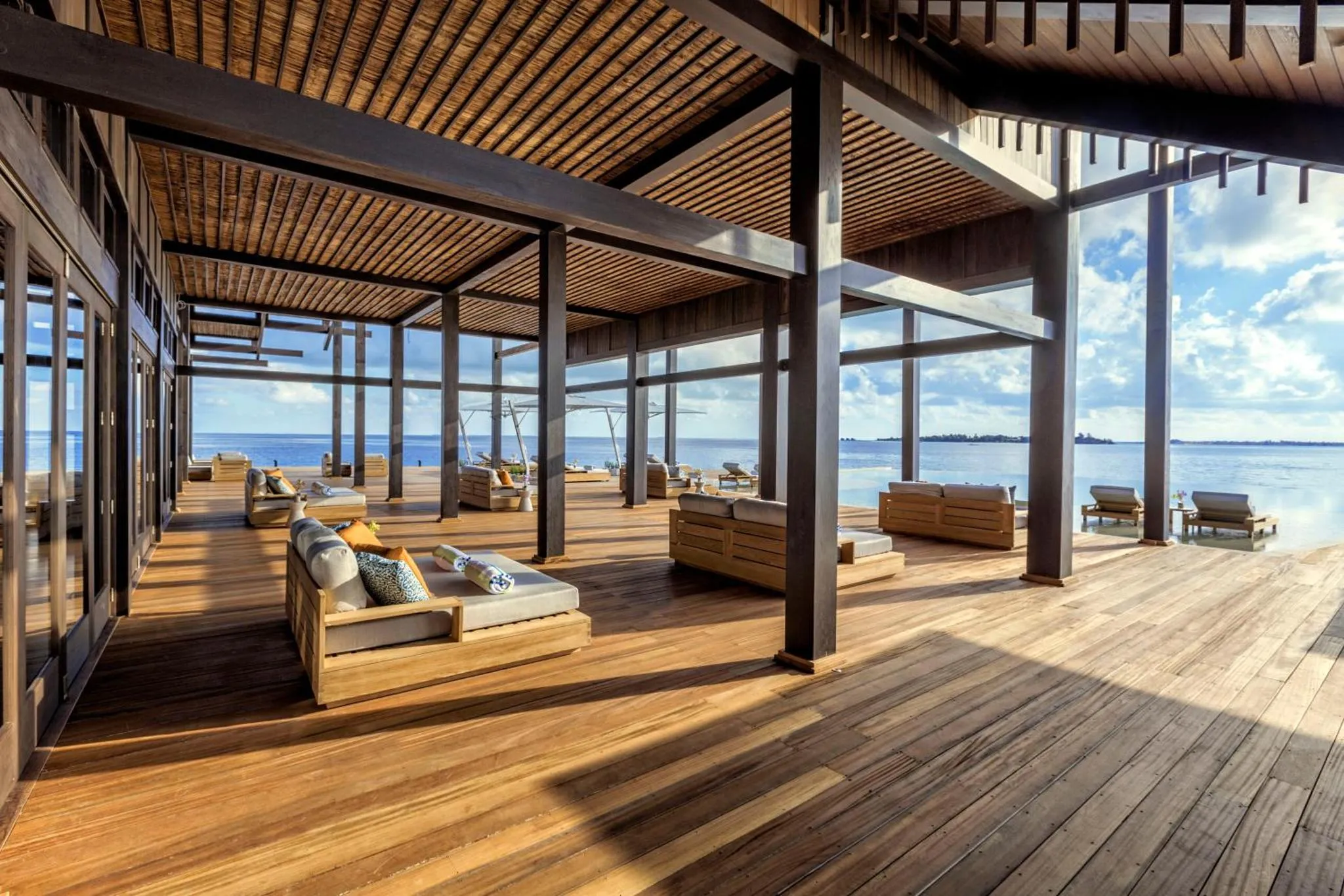 Terrasse en bois avec mobilier de détente face à la mer.