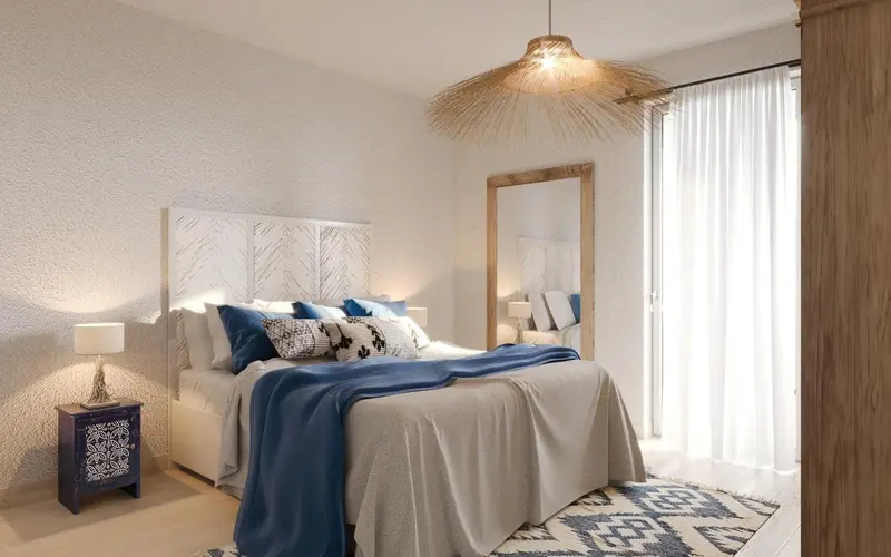 Une chambre lumineuse avec un grand lit recouvert d'une courtepointe bleue et de coussins décoratifs.