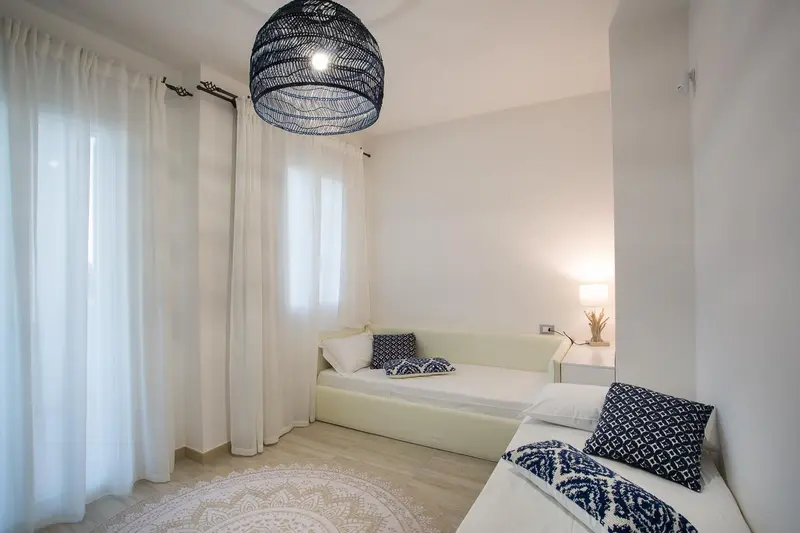 Une chambre lumineuse avec un lit simple et des rideaux blancs.
