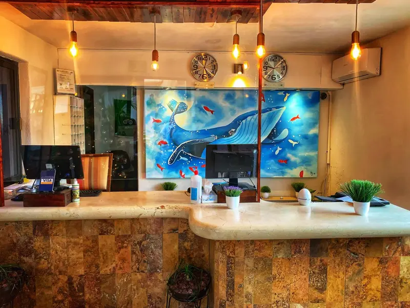 Un comptoir d'accueil en pierre avec des horloges murales et une peinture marine.
