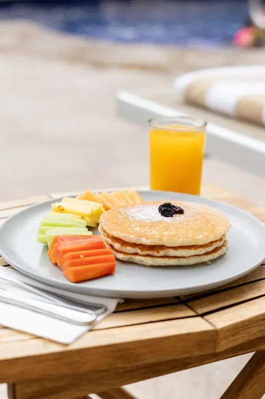 Assiette de crêpes et de fruits frais sur une table en bois.