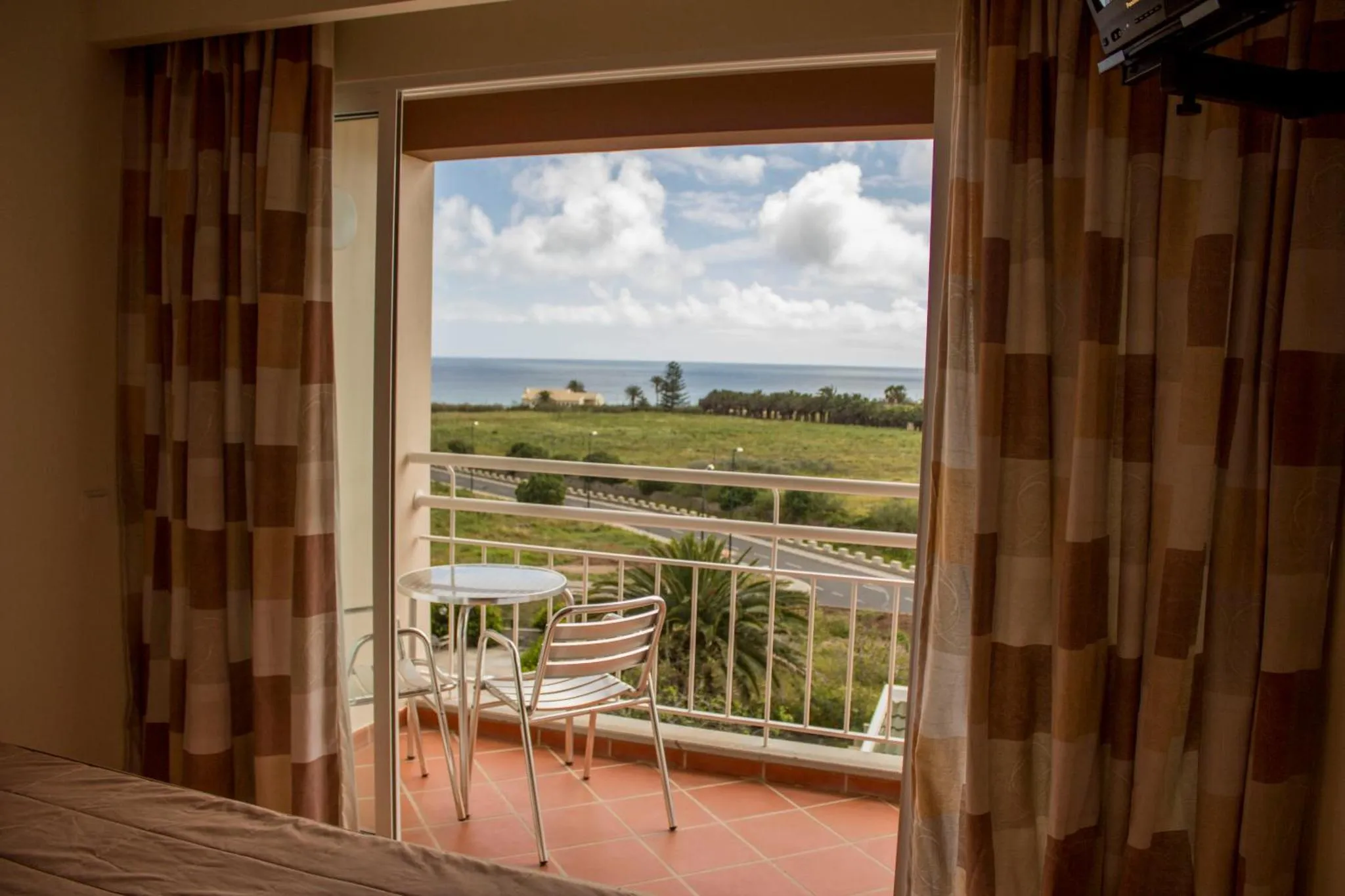Une terrasse avec une table et des chaises offre une vue sur la mer et la végétation.