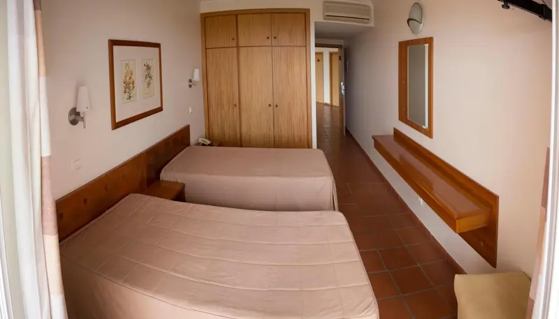Une chambre avec deux lits simples et un grand placard en bois.