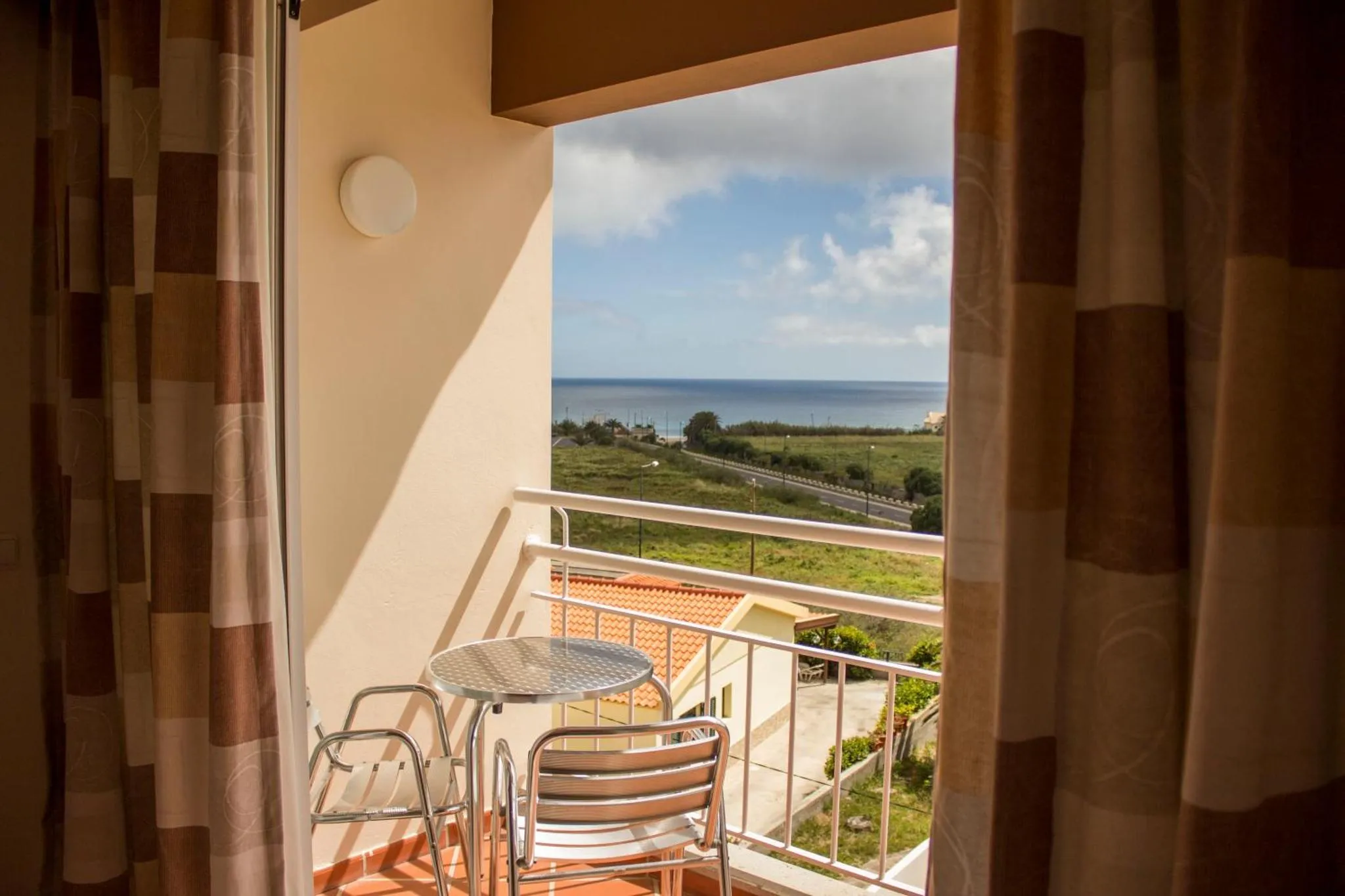 Vue sur la mer depuis un balcon avec une petite table et des chaises.