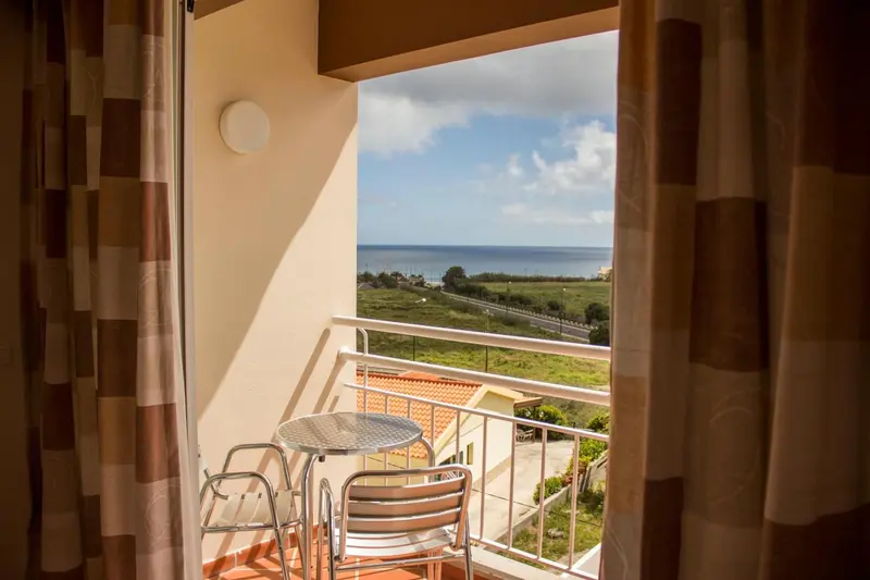 Vue sur la mer depuis un balcon avec une petite table et des chaises.