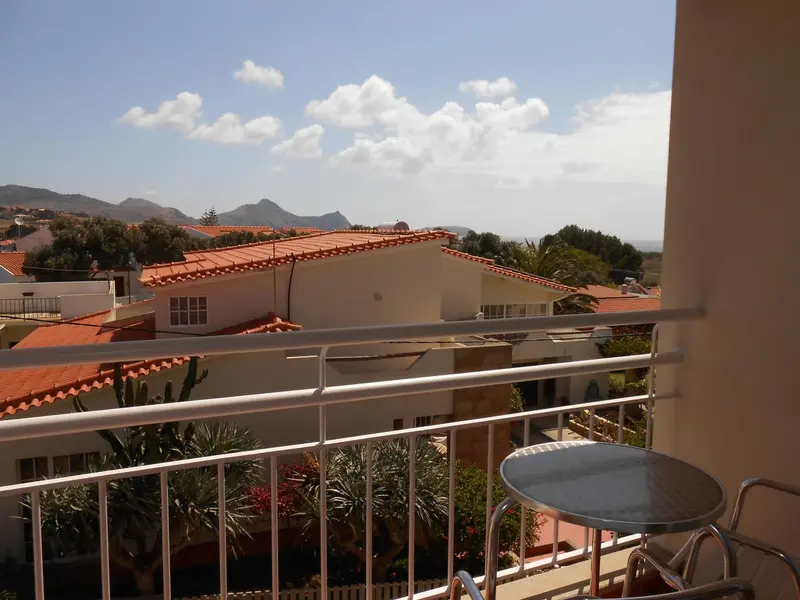 Vue d'un paysage montagneux depuis une terrasse ensoleillée.