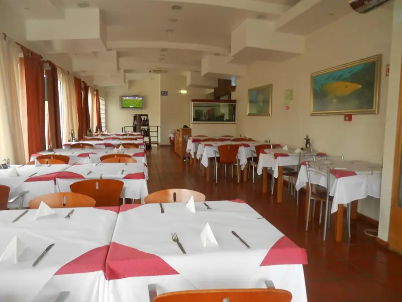 Une salle lumineuse avec des tables dressées pour un repas.