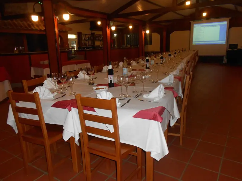 Une longue table est dressée pour un repas dans une salle lumineuse.