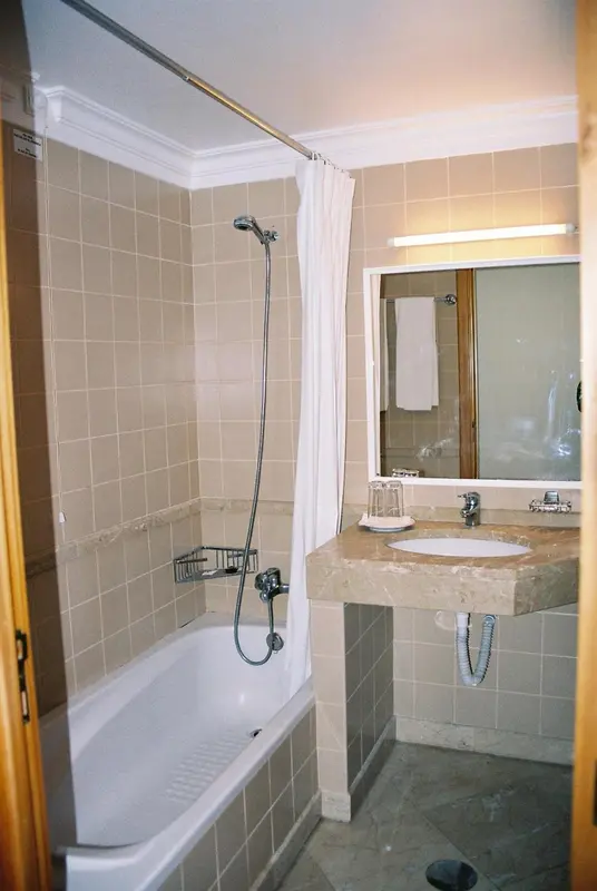 Une salle de bain carrelée avec baignoire et miroir.