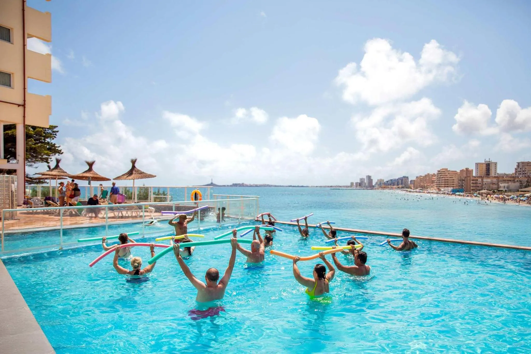 Des personnes pratiquent une activité aquatique dans une piscine en bord de mer.