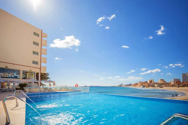 Piscine à débordement avec vue sur la mer et la plage.