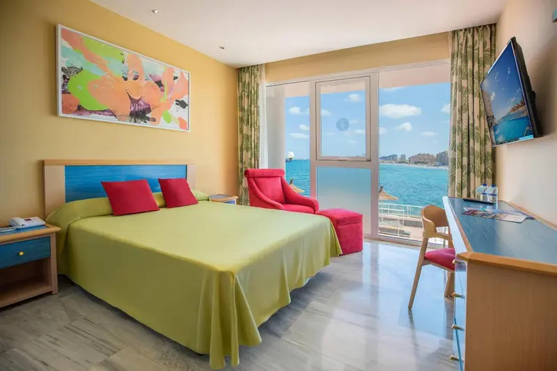 Une chambre lumineuse avec un lit fait et une vue sur la mer.
