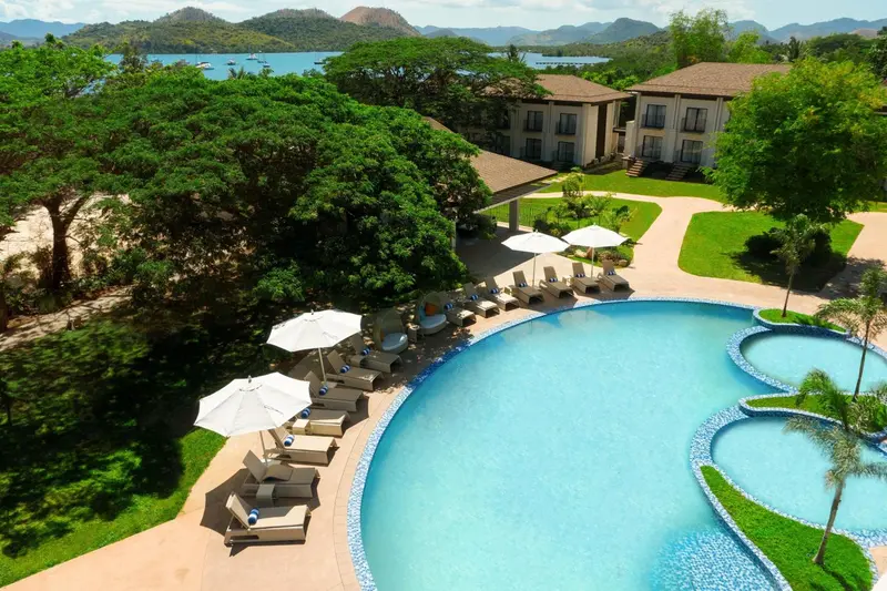 Vue aérienne d'un complexe hôtelier avec piscine et végétation luxuriante.