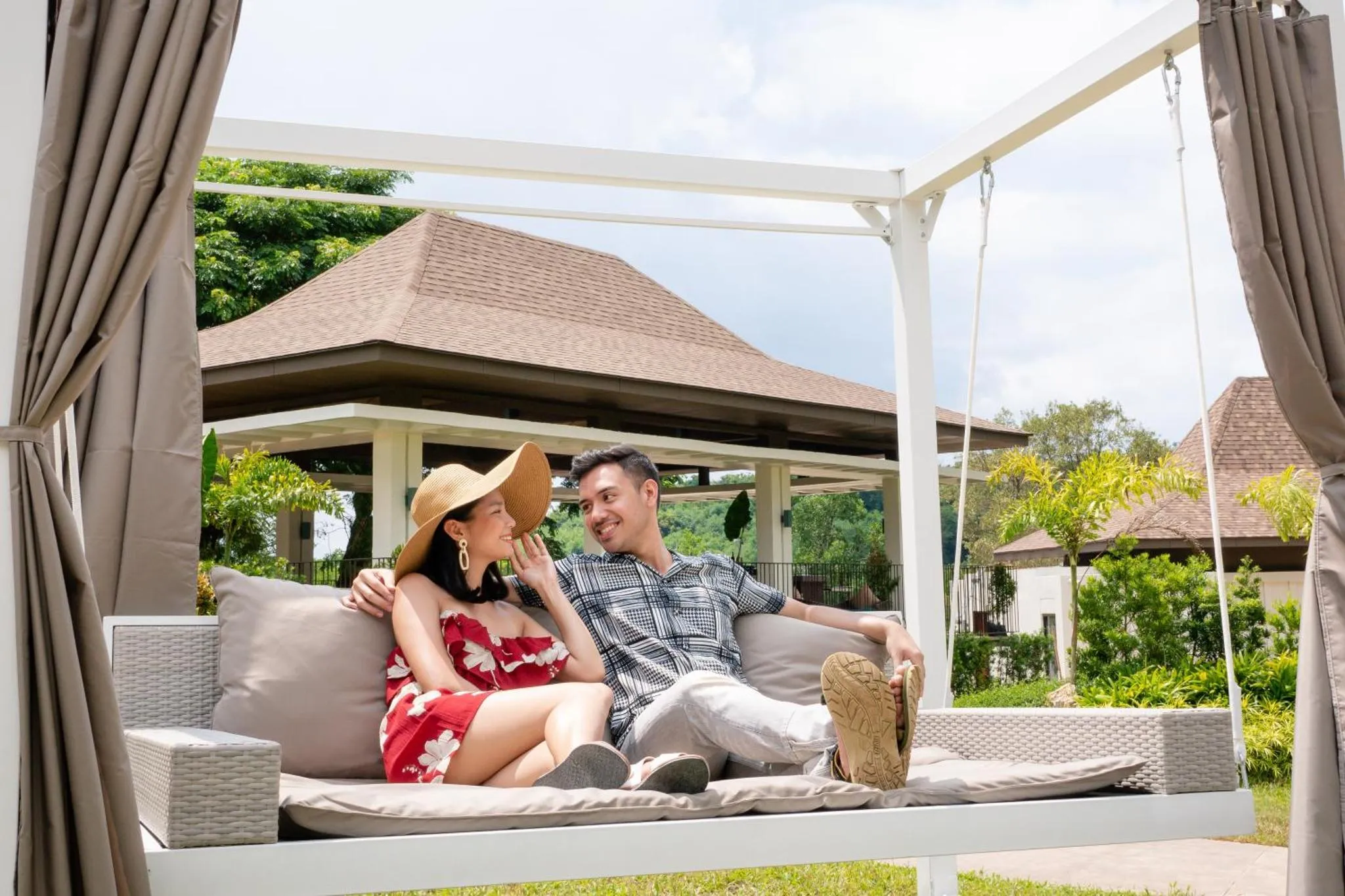 Un couple se détend sur une balancelle dans un jardin tropical.