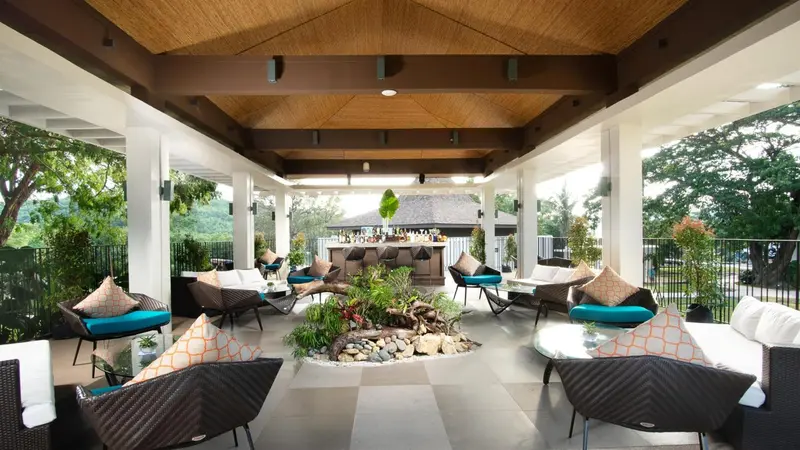 Espace de détente extérieur avec mobilier confortable et végétation tropicale.