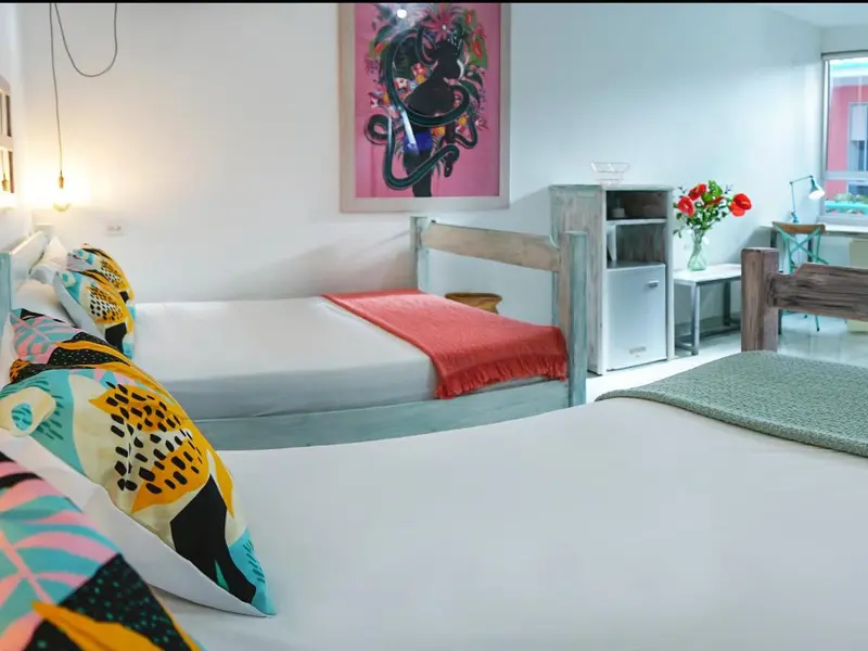 Une chambre lumineuse avec deux lits simples et une décoration colorée.