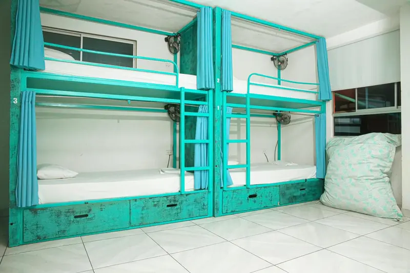 Lits superposés turquoise dans un dortoir lumineux.