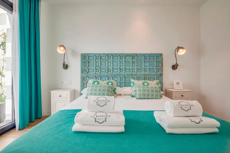 Lit recouvert d'une couverture turquoise et de coussins décoratifs dans une chambre.