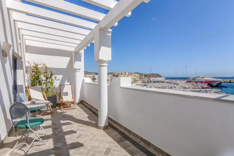 Terrasse avec mobilier d'extérieur et vue sur un port de plaisance.