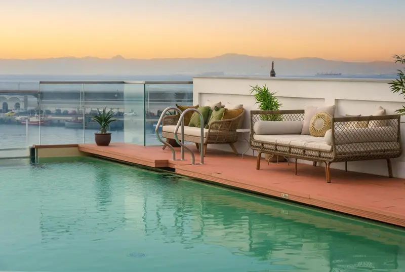 Terrasse avec mobilier de détente et piscine offrant une vue sur la mer et le port.