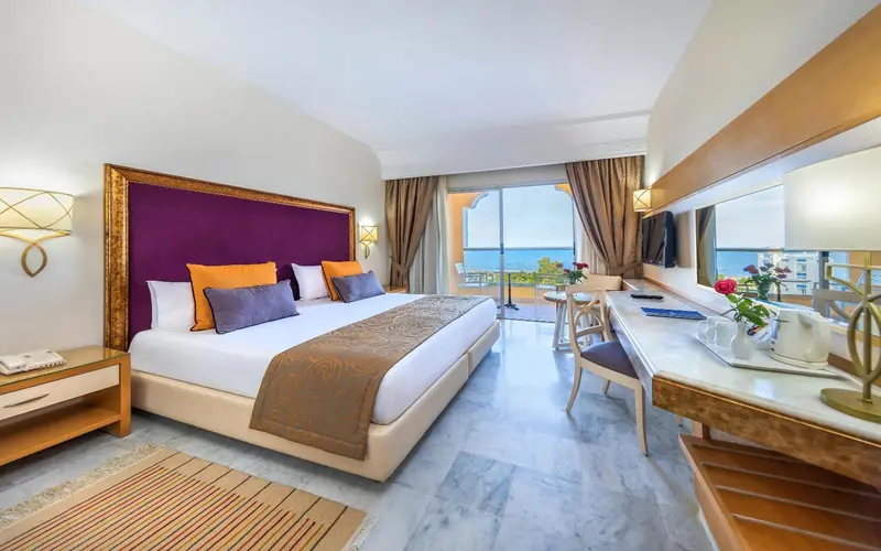 Chambre lumineuse avec un grand lit et une vue sur la mer.