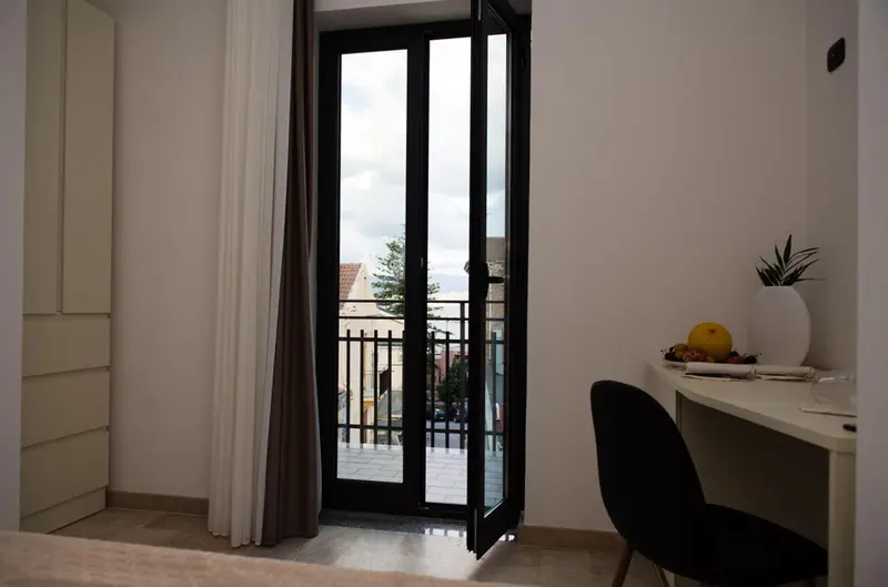 Une chambre lumineuse s'ouvre sur un balcon avec vue sur la ville.
