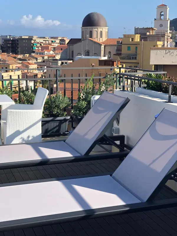 Terrasse avec transats blancs et vue sur la ville.