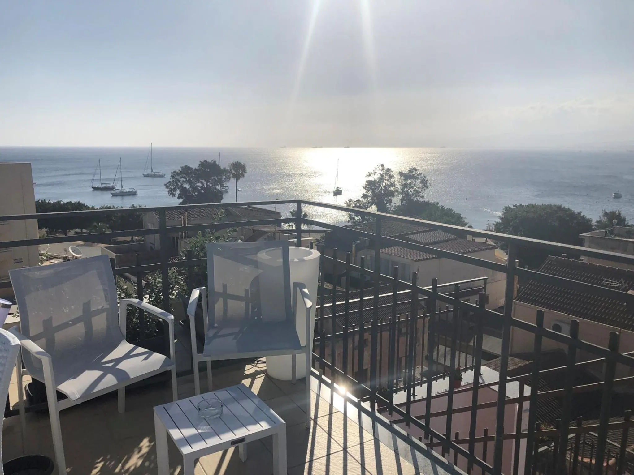 Terrasse aménagée avec transats et vue sur la mer scintillante.