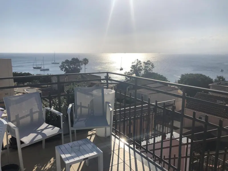 Terrasse aménagée avec transats et vue sur la mer scintillante.