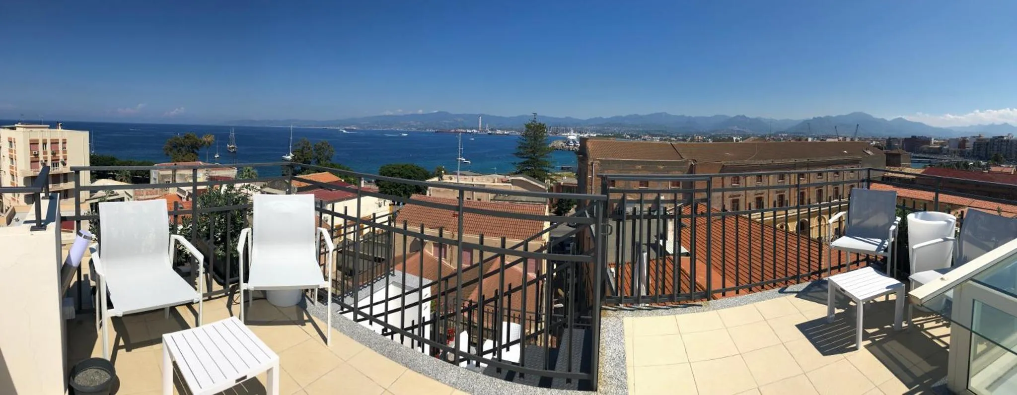 Terrasse avec mobilier d'extérieur offrant une vue sur la mer et les montagnes.
