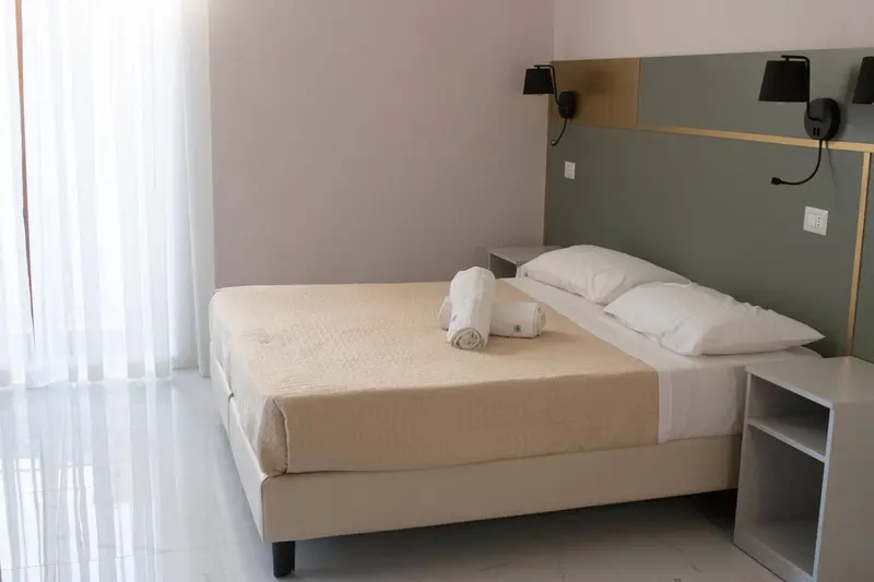 Une chambre lumineuse avec un grand lit et des rideaux blancs.