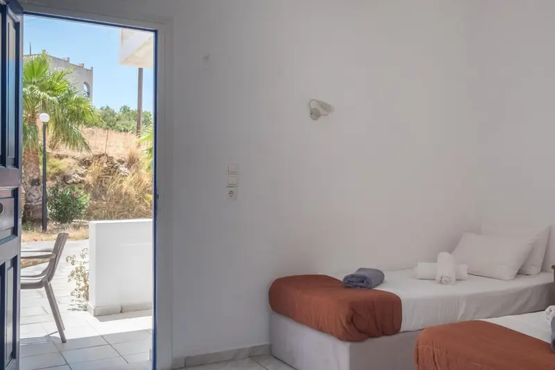 Une chambre lumineuse avec un lit simple et une vue sur un jardin.