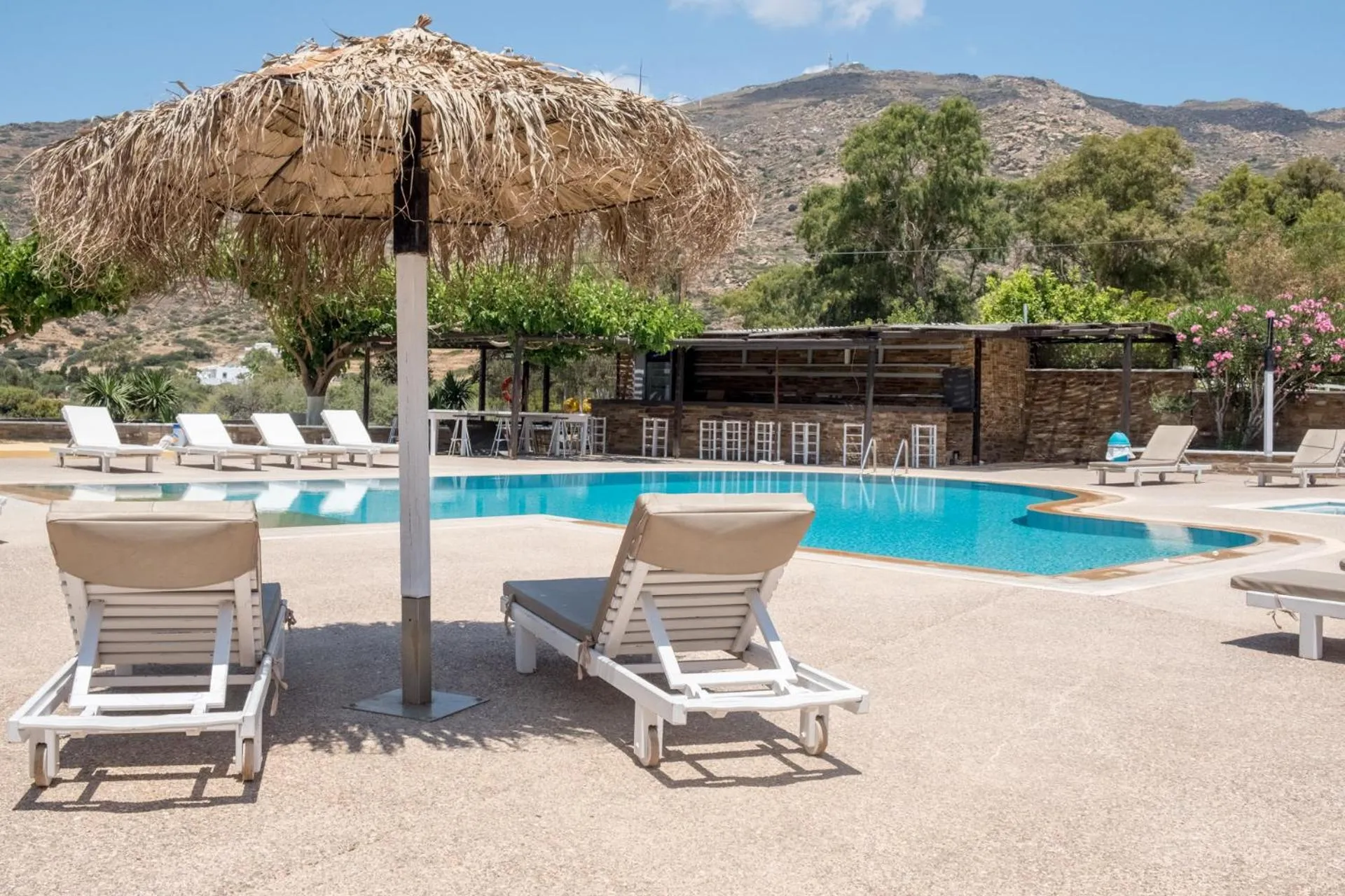 Transats et parasol ombragent une piscine bordée d'une terrasse.
