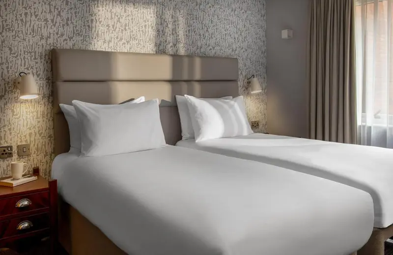 Un lit double avec des oreillers blancs dans une chambre lumineuse.