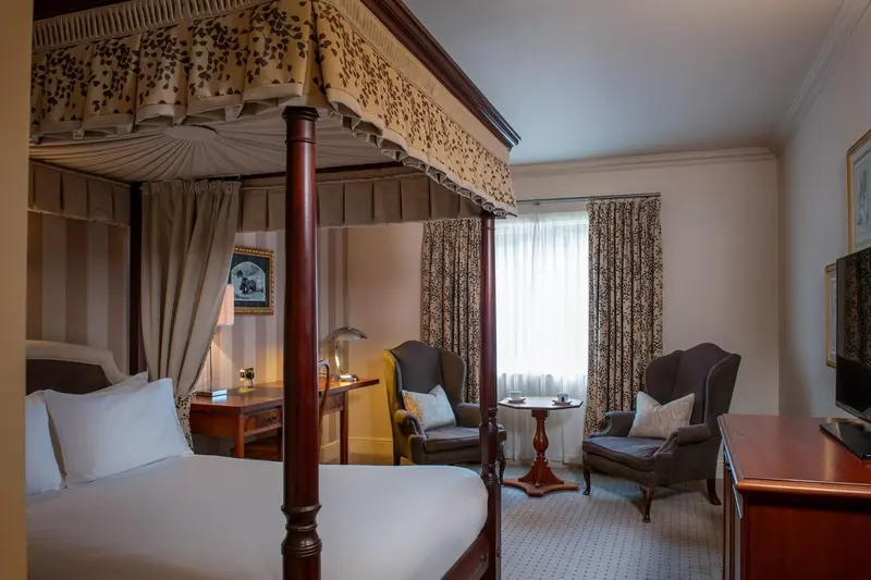 Une chambre à coucher avec un lit à baldaquin et deux fauteuils.