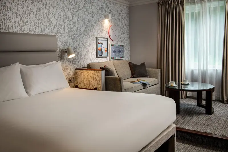 Une chambre lumineuse avec un lit confortable et un coin salon.