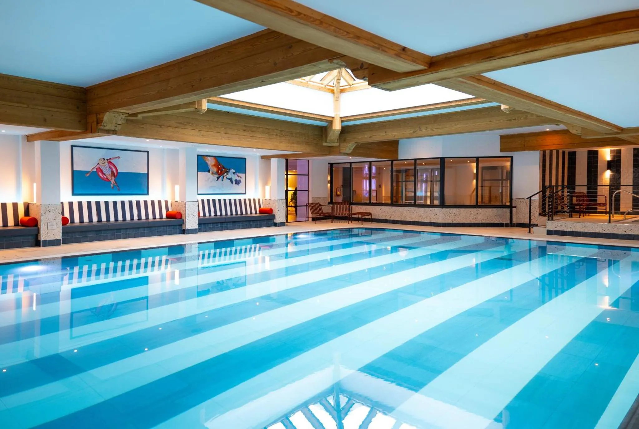 Une piscine intérieure rectangulaire avec des lignes bleues claires et un espace de détente sur le côté.
